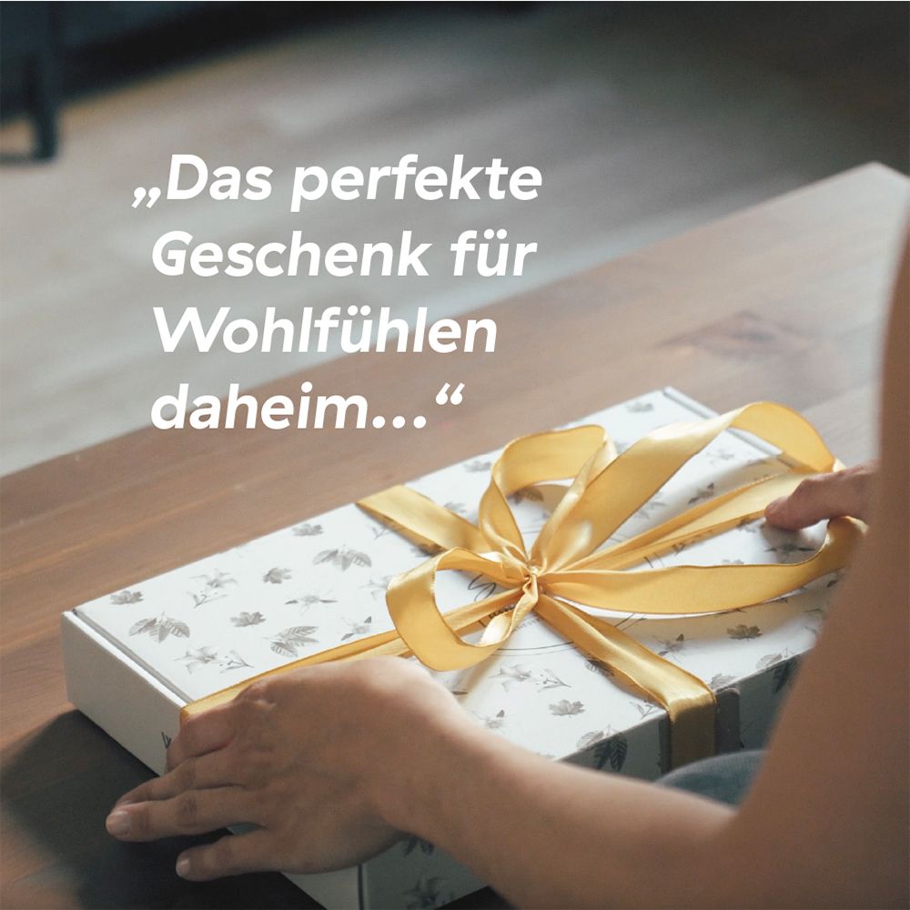 Une personne ouvre une boîte cadeau avec un rubet doré. Texte : "Le cadeau parfait pour le bien-être à la maison..."