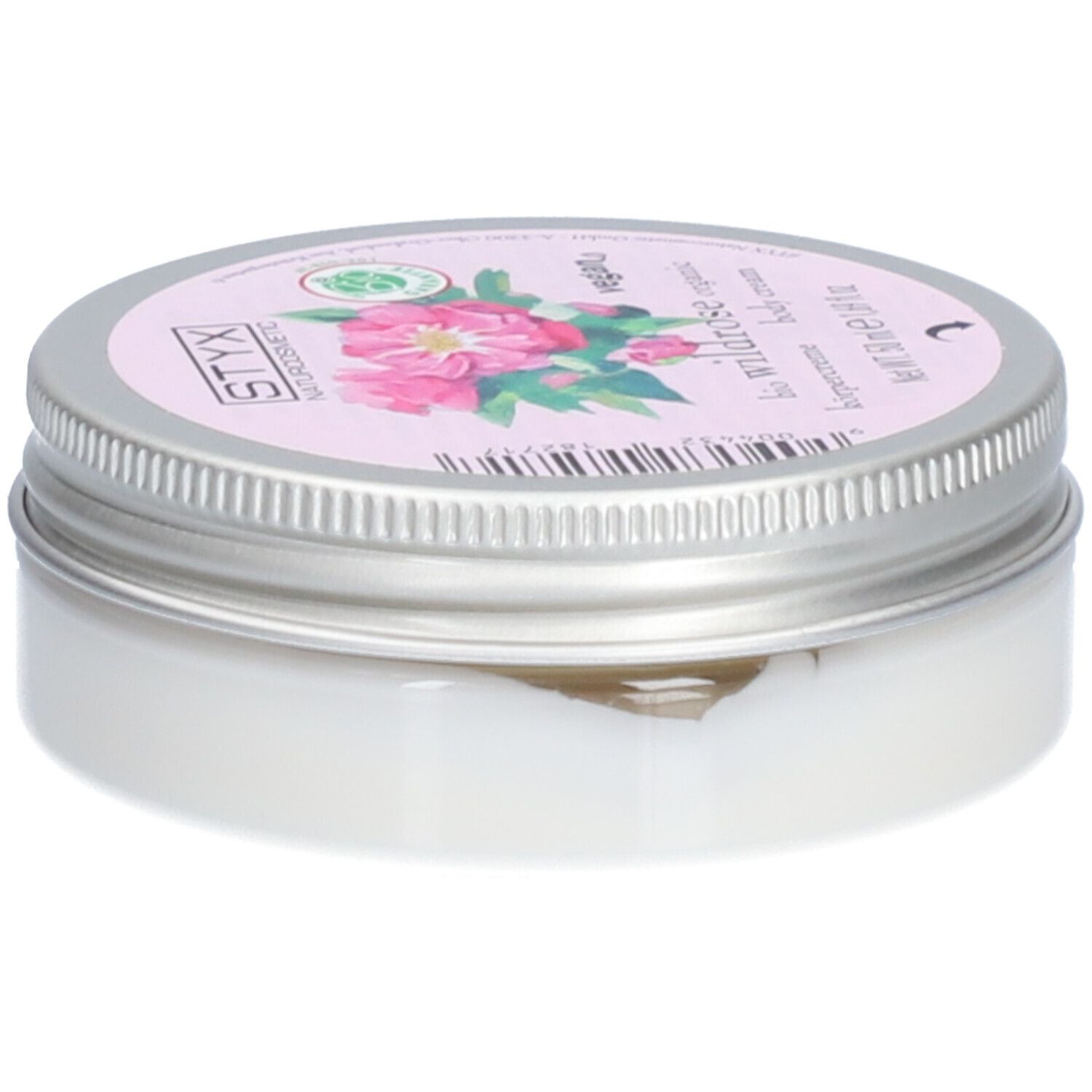 Pot de crème avec couvercle. Sur le couvercle : STYX Naturkosmetik, Wildrose, vegan. Étiquette rose avec fleurs de rose. Pot en métal.