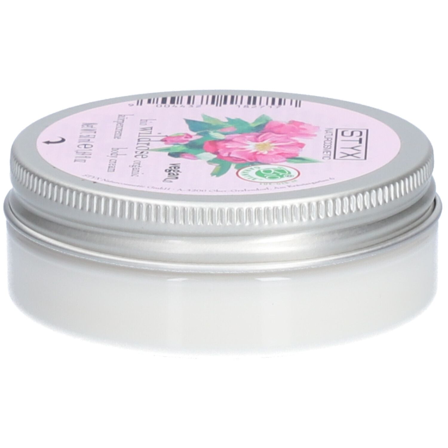 Pot de crème avec couvercle. Sur le couvercle : STYX Naturkosmetik, Wildrose, vegan. Étiquette rose avec fleurs de rose. Pot en métal.