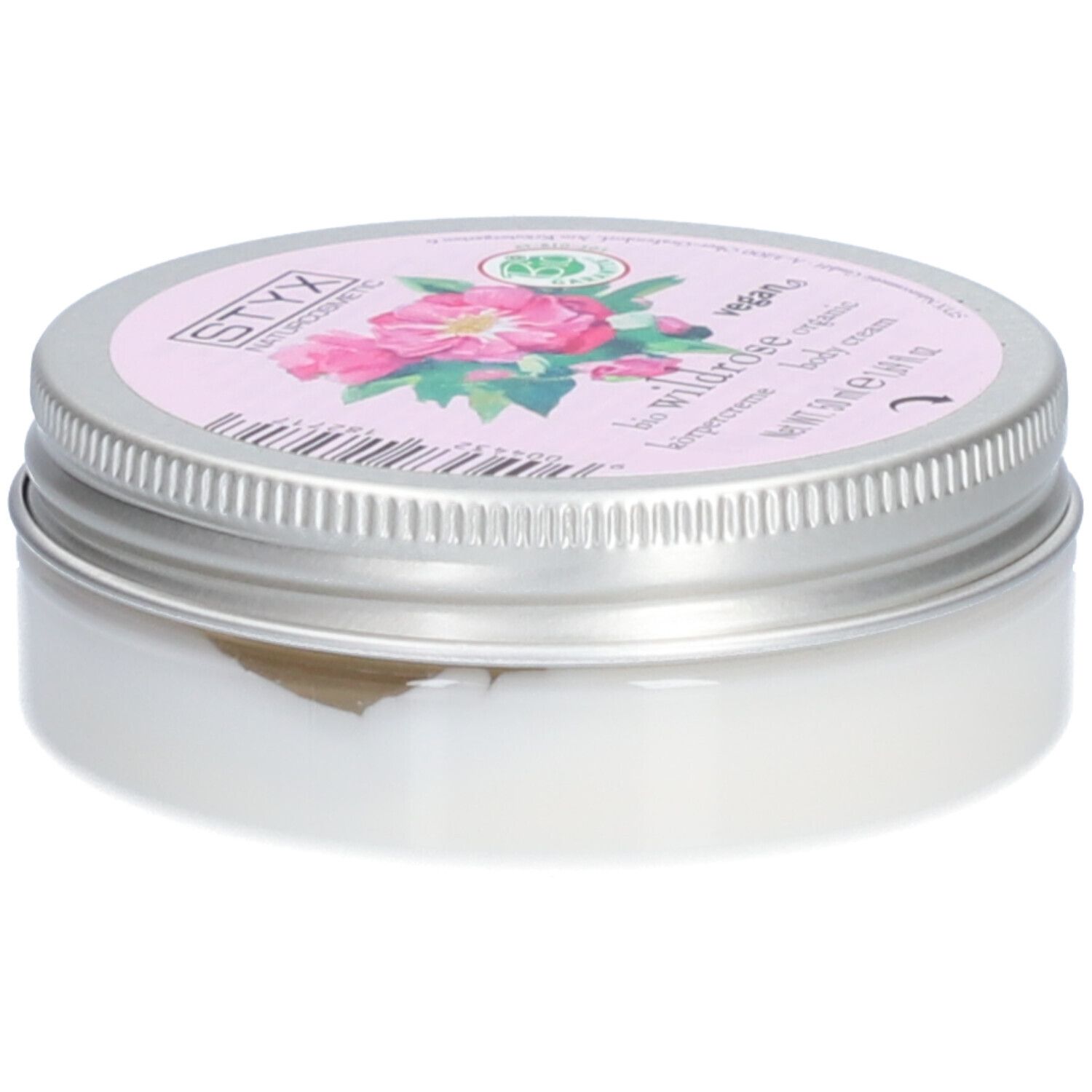 Pot de crème avec couvercle. Sur le couvercle : STYX Naturkosmetik, Wildrose, vegan. Étiquette rose avec fleurs de rose. Pot en métal.