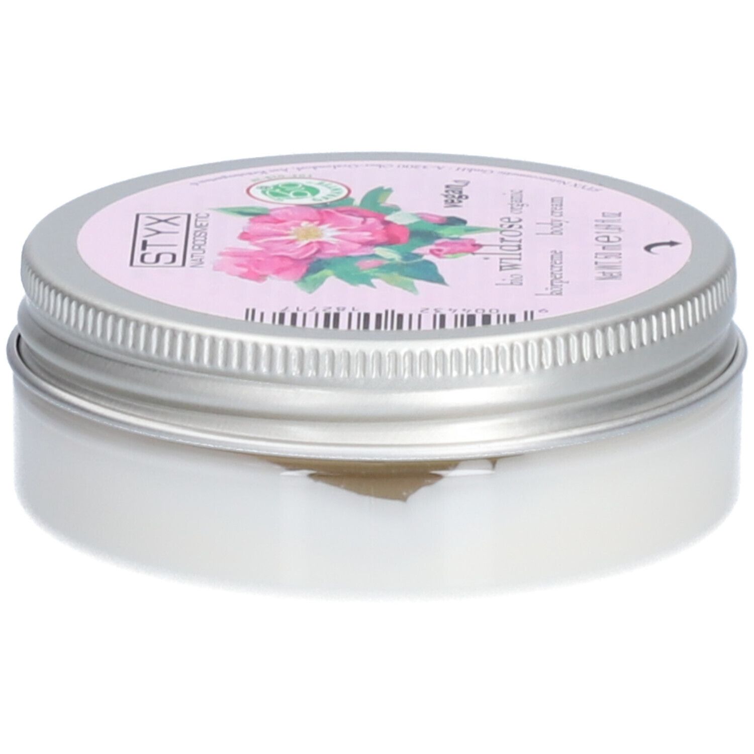 Pot de crème avec couvercle. Sur le couvercle : STYX Naturkosmetik, Wildrose, vegan. Étiquette rose avec fleurs de rose. Pot en métal.