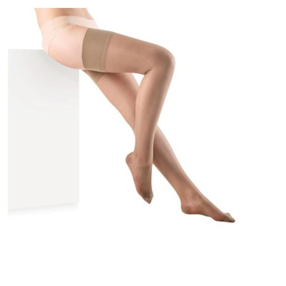 Jambes avec bas de compression. Bas couleur chair, jambe sur cube blanc. Produit visible.