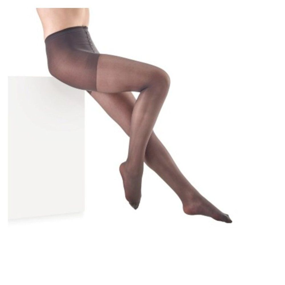 Collants sur fond blanc. Couleur foncée. Femme assise sur un bloc blanc.