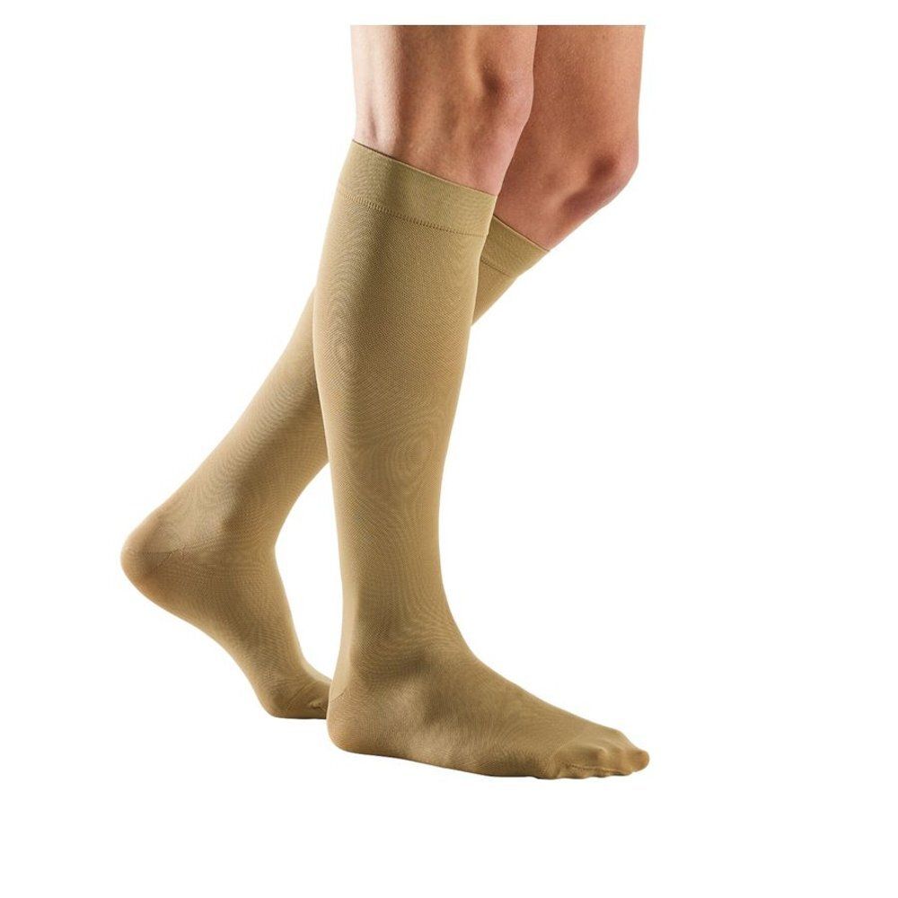 Bas genou beiges. Vue latérale des jambes. Les bas couvrent les pieds et le bas des jambes.