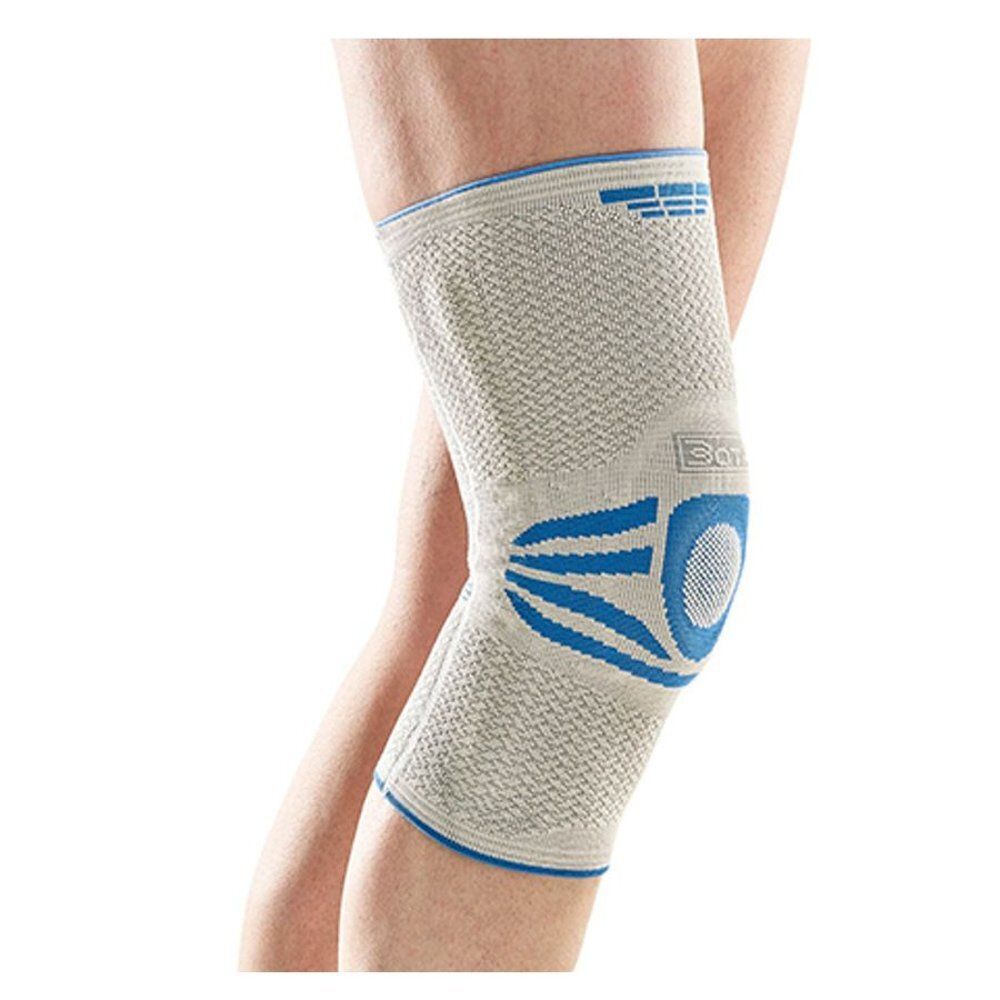 Genouillère sur une jambe. Beige et bleu. Détails visibles : logo, texture du matériau, accents bleus, zone du genou.