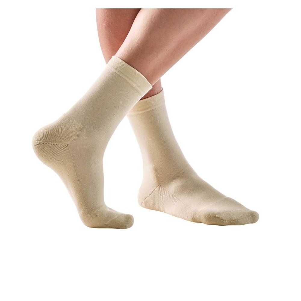 Chaussettes beiges sur des pieds. La tige des chaussettes arrive sous le genou.