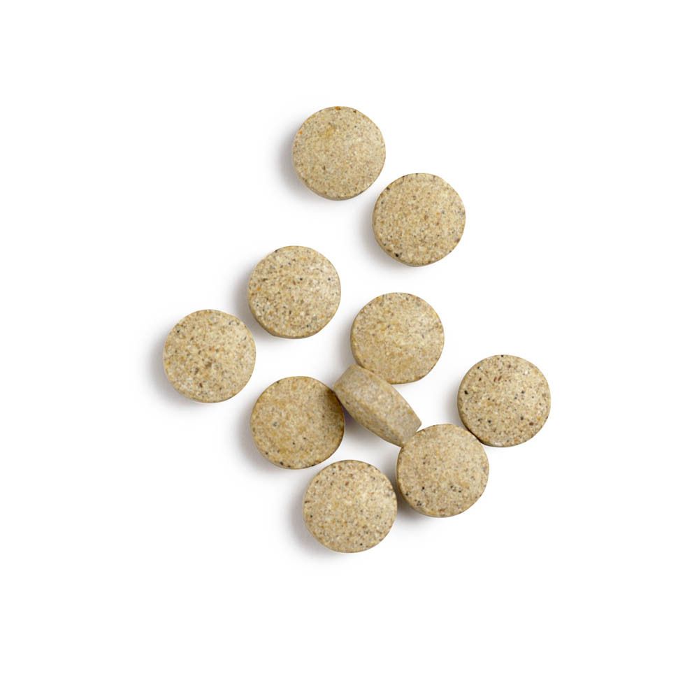 Comprimés ronds, beiges. Sur fond blanc. Quelques comprimés dispersés.