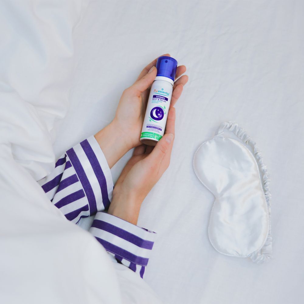 Main pulvérisant le spray détente Puressentiel dans l'air.