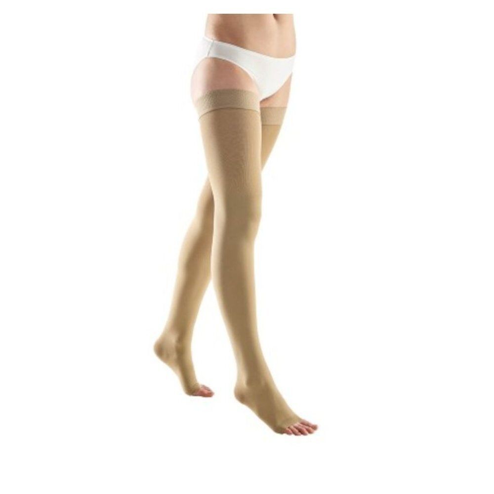 Bas de compression beiges. Design à bout ouvert. Au-dessus du genou. Sur fond blanc.