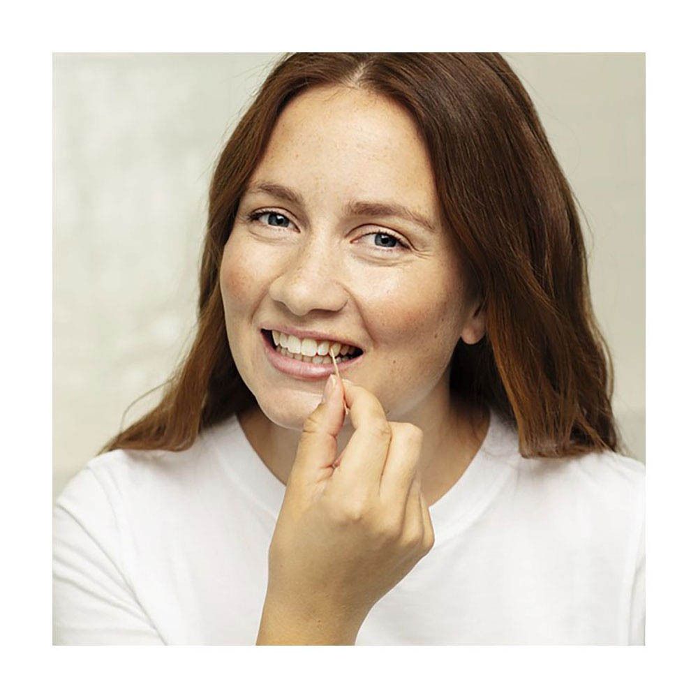 Femme utilisant un cure-dent. Gros plan. Peau claire, t-shirt blanc.