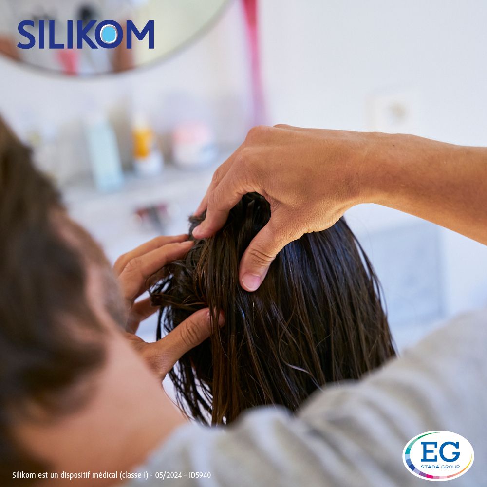 Personne vaporisant les cheveux avec Silikom Once Spray Anti-poux.