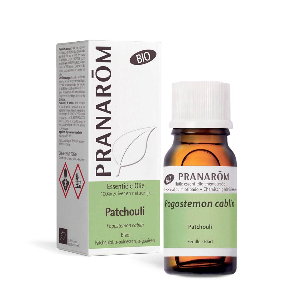Flacon en verre brun avec bouchon blanc et étiquette. Texte: Pogostemon cablin, Patchouli. 10 ml. Avec boîte.