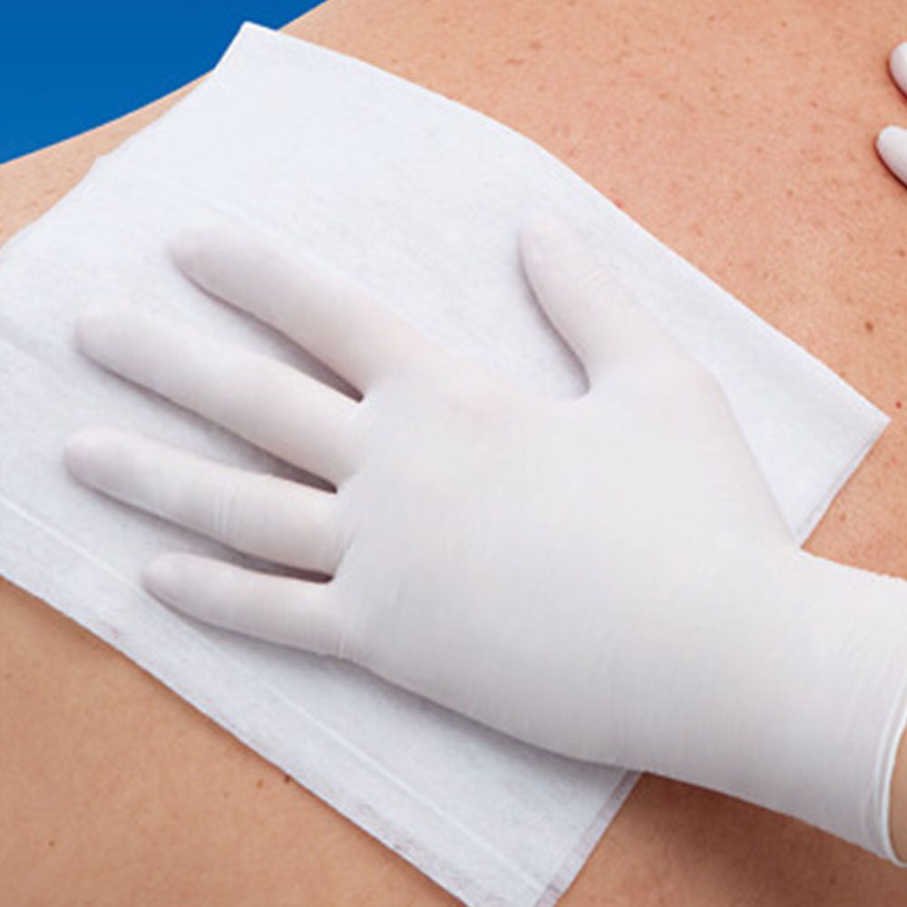 Gants en nitrile blancs sur une compresse blanche, sur le dos d'une personne.