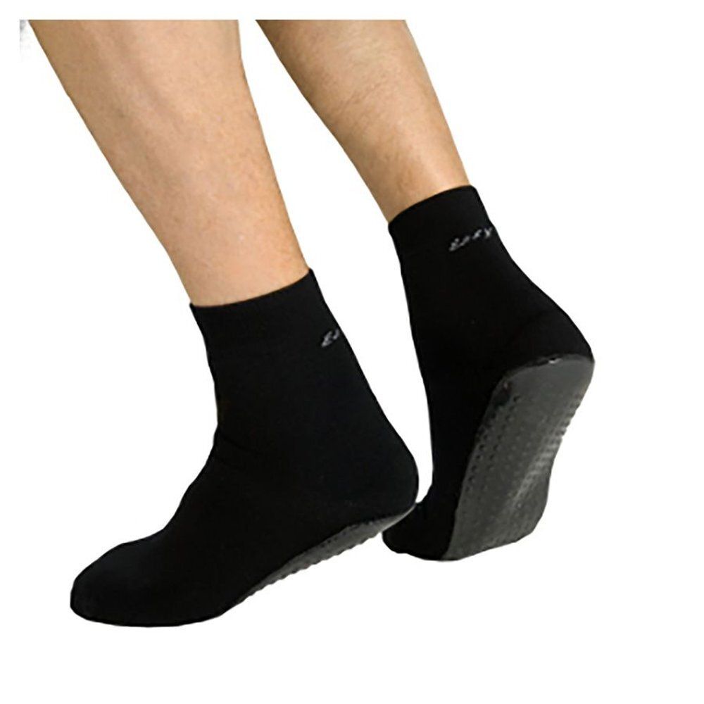 Chaussettes noires avec semelle caoutchoutée. Pieds dans des chaussettes. Semelle caoutchoutée visible. Marque non reconnaissable.