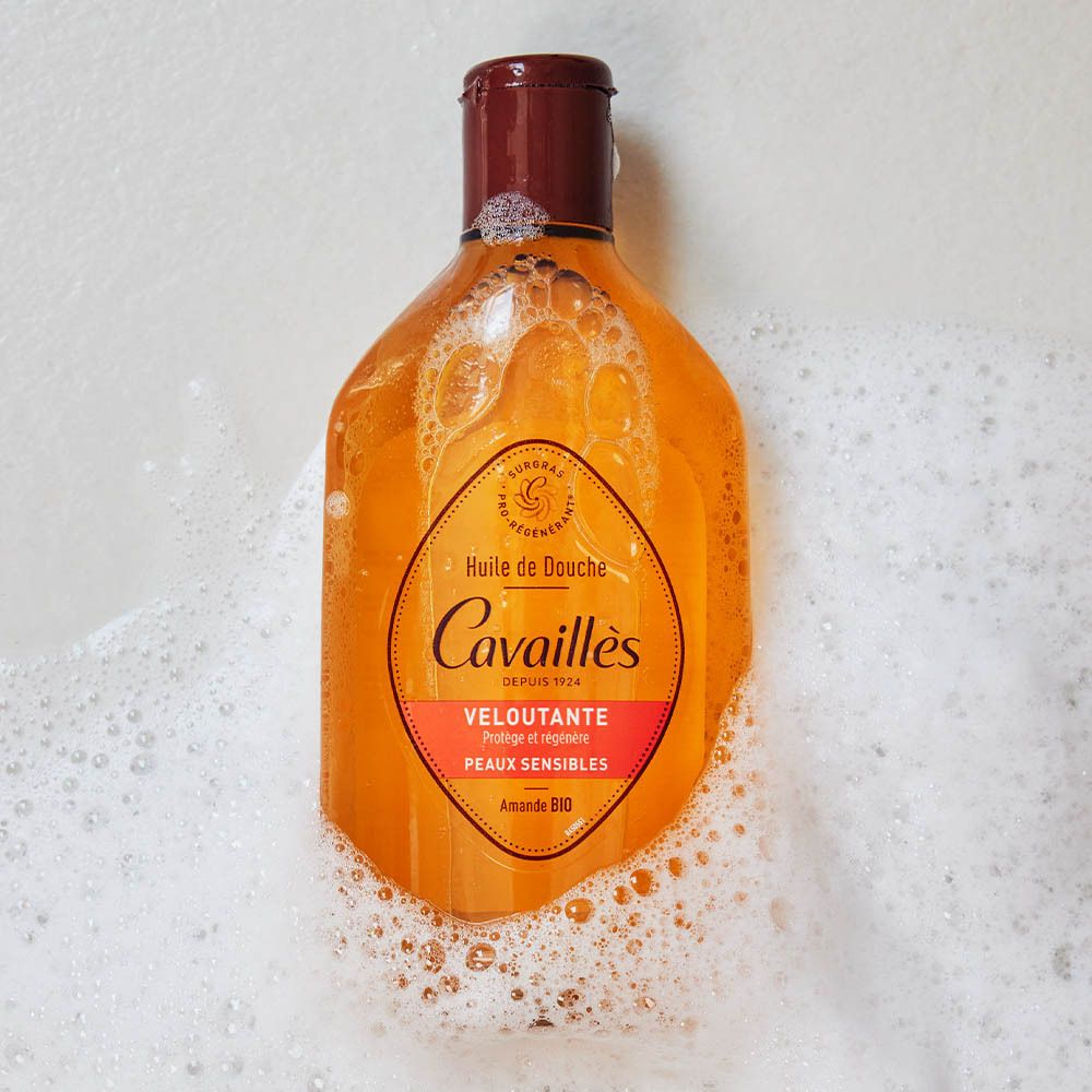 Flacon dans la mousse. Inscription: Rogé Cavaillès, Huile de Douche Veloutante, Amande Bio. Dans un bain moussant.