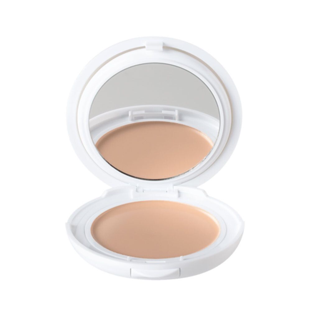 Boîtier de maquillage compact blanc ouvert, avec miroir et fond de teint clair. Produit ouvert, fond de teint clair visible.