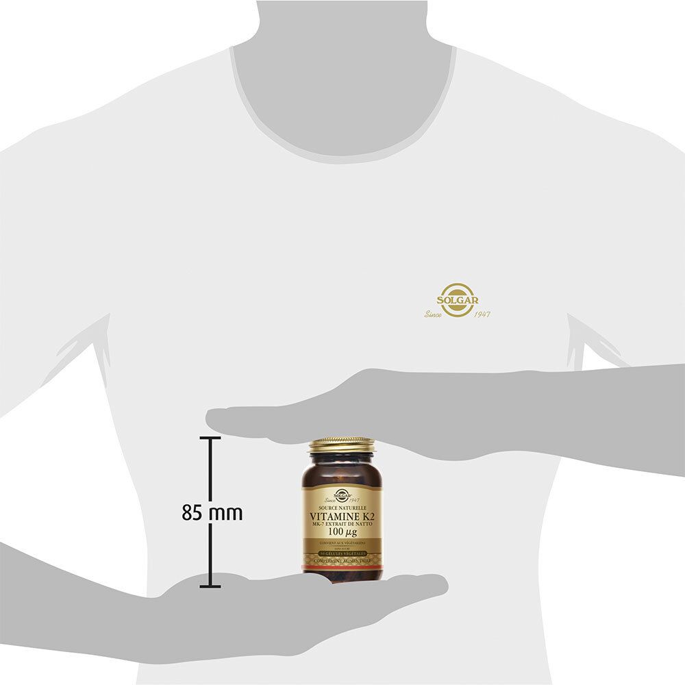 Homme tenant flacon. Sur flacon: Vitamine K2 100 µg. Dimensions: 85 mm.