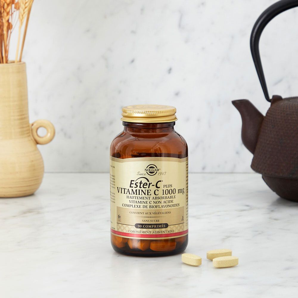 Flacon en verre avec comprimés sur une table. Décoration en arrière-plan. Nom du produit et logo visibles.