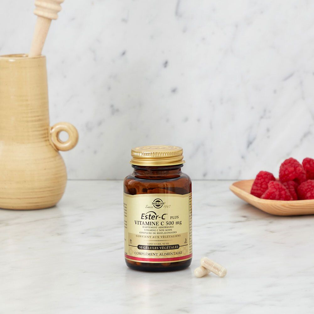 Flacon de gélules de vitamine C sur marbre. Framboises dans un bol.