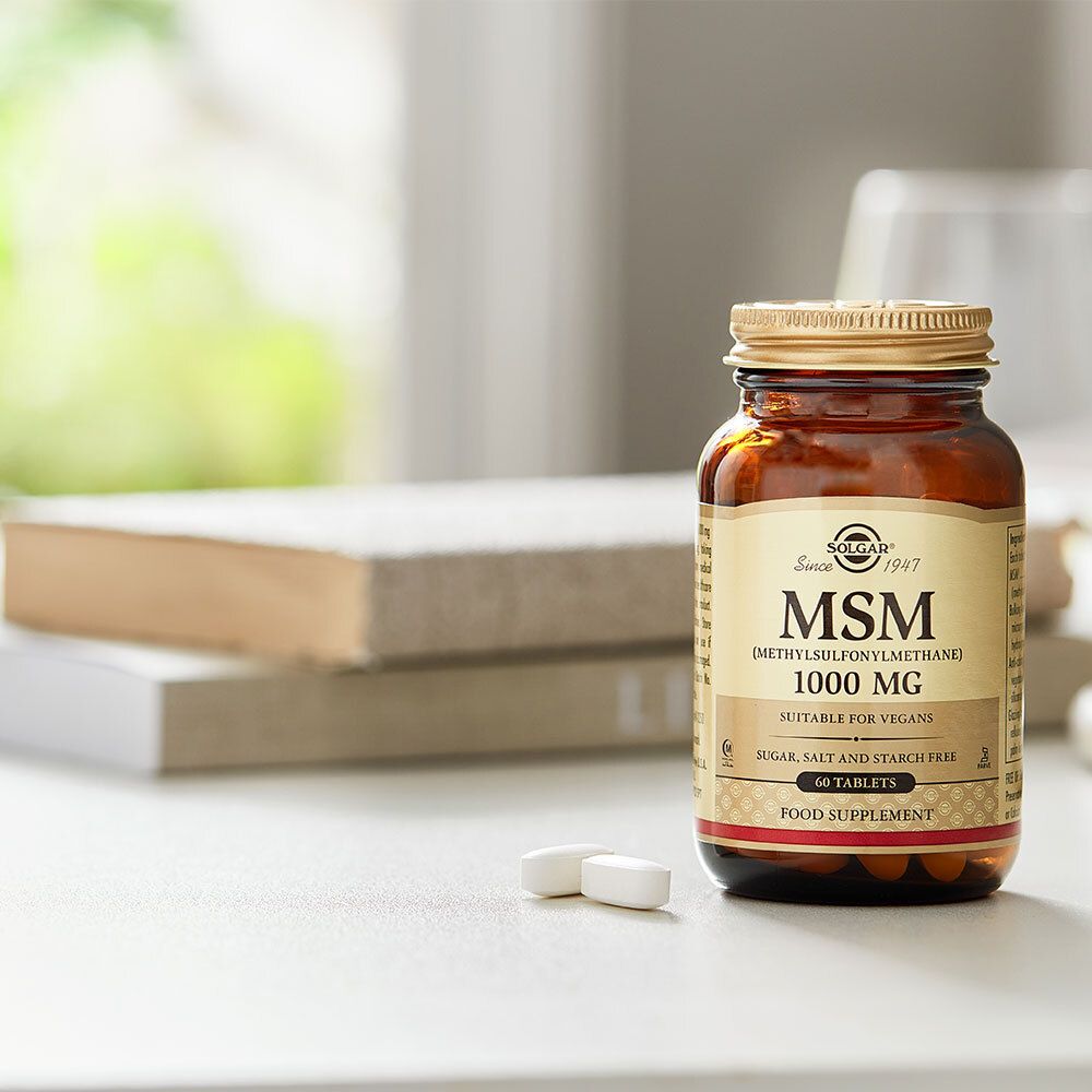 Flacon MSM 1000 mg avec comprimés sur table. Marque Solgar, 60 comprimés. Contexte de livres.