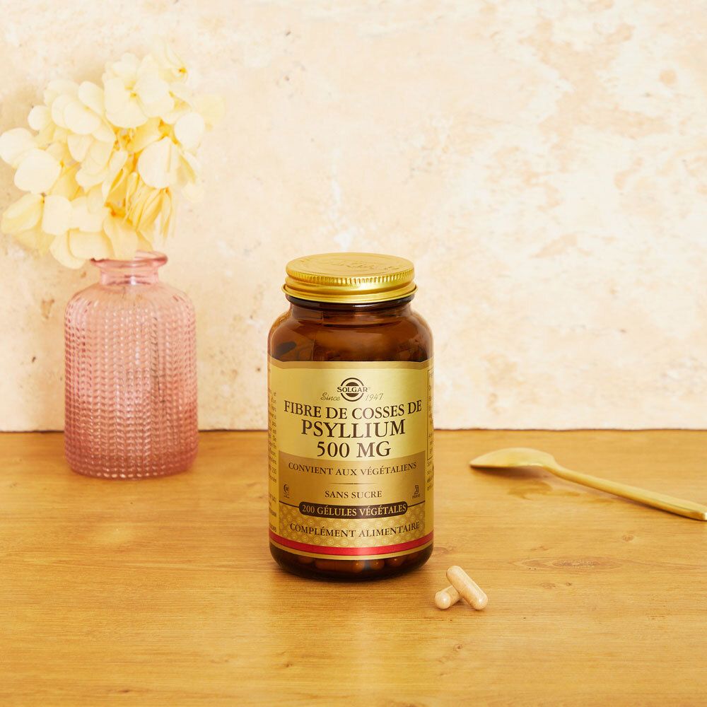 Flacon brun avec gélules et cuillère sur surface en bois. Fond : vase avec fleurs.