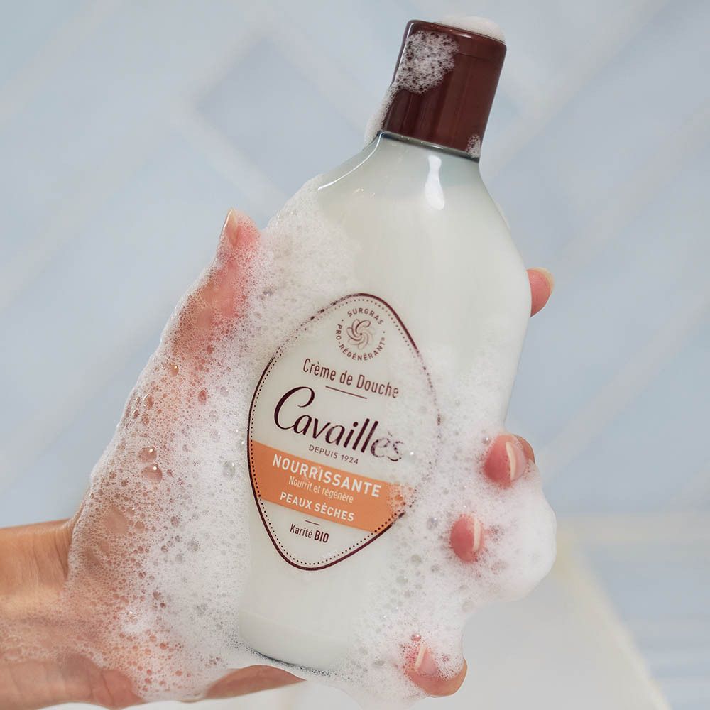 Crème de douche Rogé Cavaillès. Flacon avec bouchon marron. Produit entouré de mousse. Inscription: Nourrissante, Peaux sèches.
