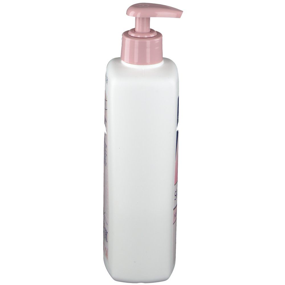 Flacon blanc avec pompe rose. Vue latérale. Inscriptions sur le flacon. Produit pour le soin de la peau.