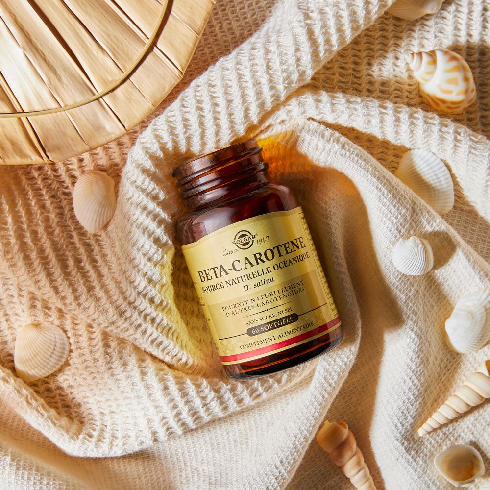 Flacon brun sur tissu crème, entouré de coquillages et décorations.