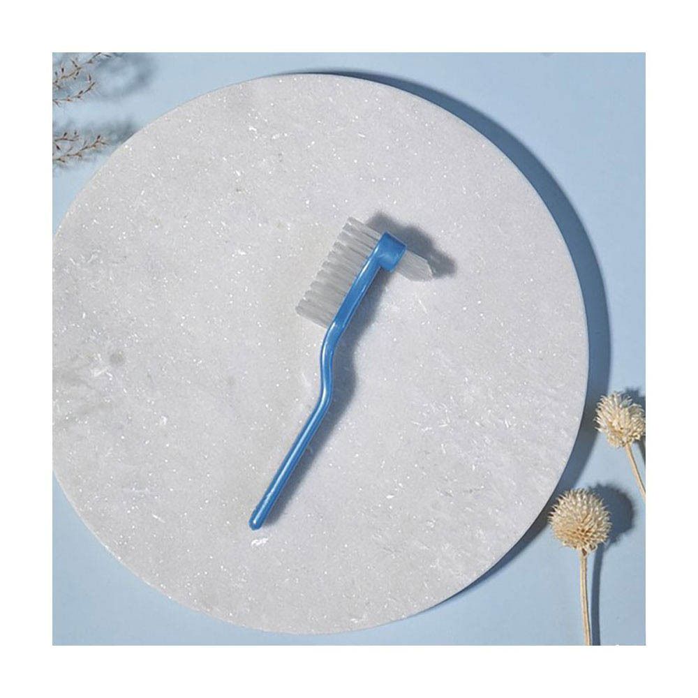 Brosse à dents bleue pour prothèses sur plaque de marbre blanc. Deux têtes de brosse avec soies blanches.