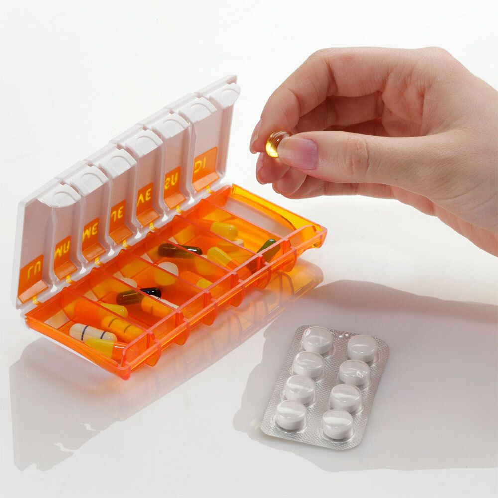 Boîte à pilules ouverte avec des médicaments, une main prend une pilule.