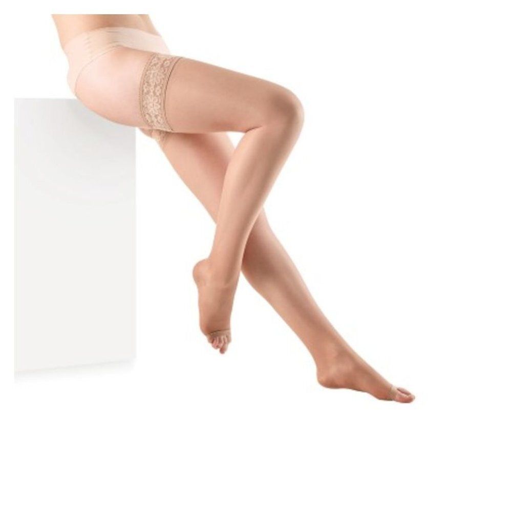 Jambes portant des bas de maintien. Bas avec dentelle sur la cuisse. Sur fond blanc.