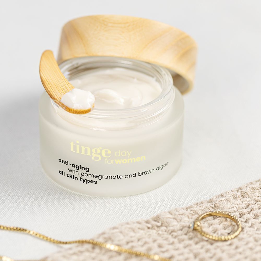 Crème de jour Tinge pour femmes. Pot en verre avec couvercle en bois. Inscription : Anti-âge, grenade et algues brunes, tous types de peau.