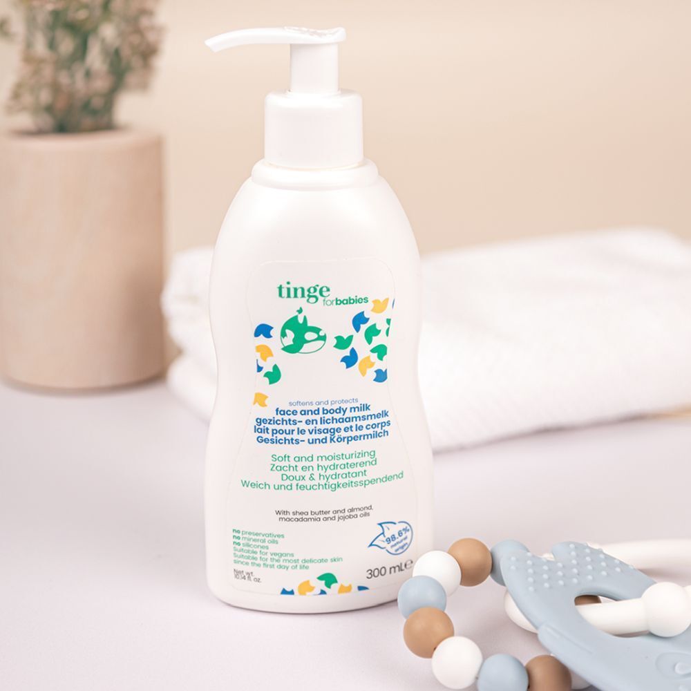 Flacon blanc avec pompe, lait visage et corps pour bébés, sur une table avec des accessoires pour bébé.
