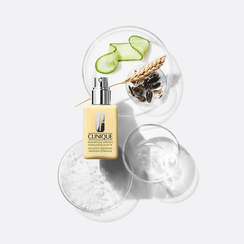 Lotion hydratante Clinique dans un flacon jaune avec pompe, à côté de tranches de concombre et d'épis de blé.