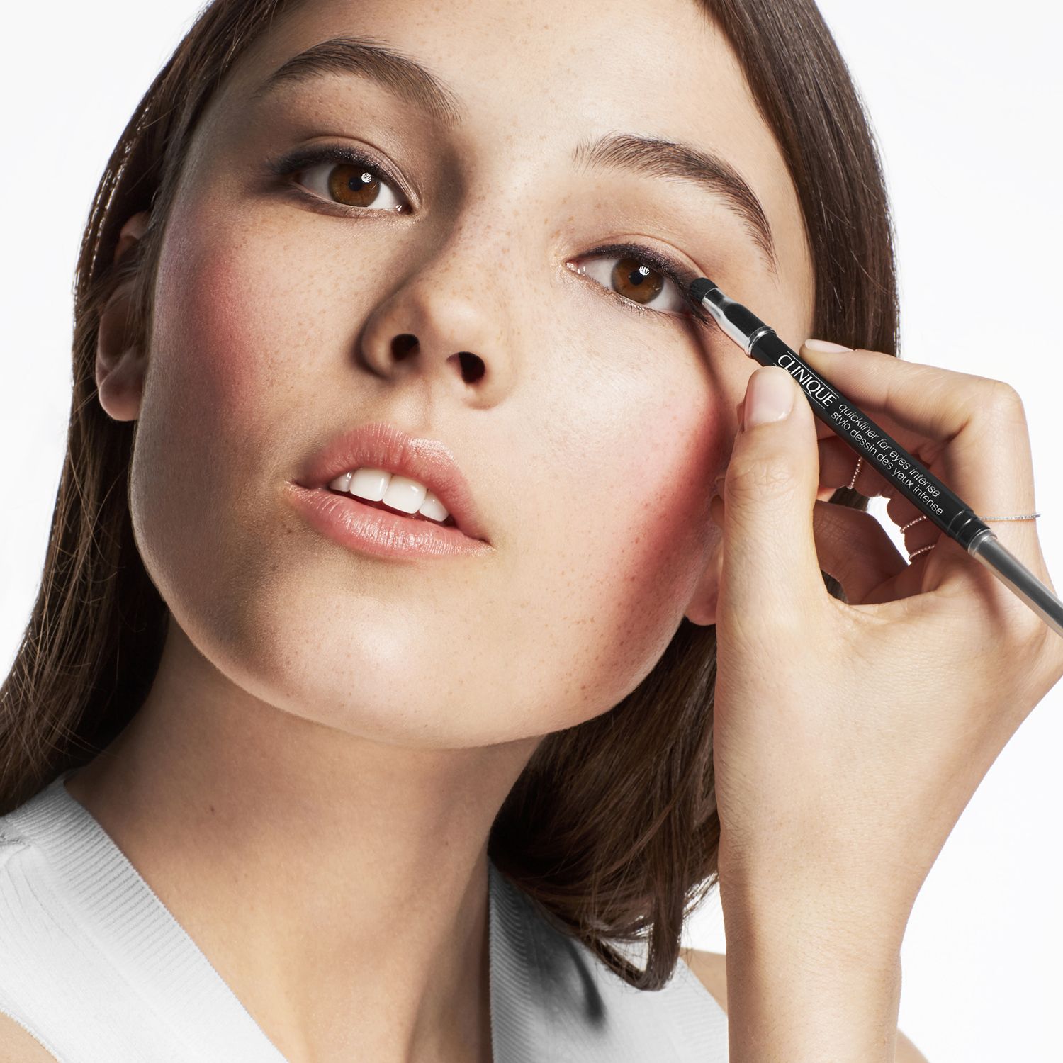 Femme appliquant de l'eyeliner. Produit visible.