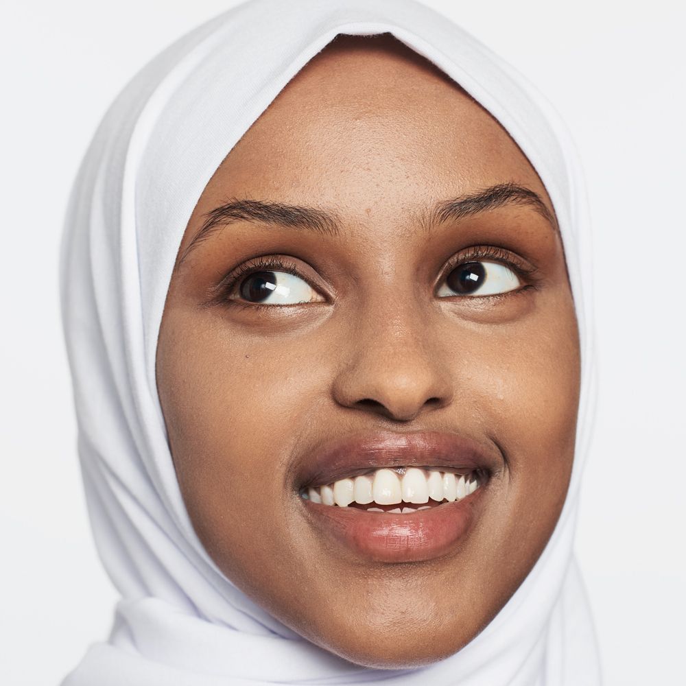 Portrait d'une femme portant un hijab. Elle sourit. Teint et traits du visage clairement visibles.