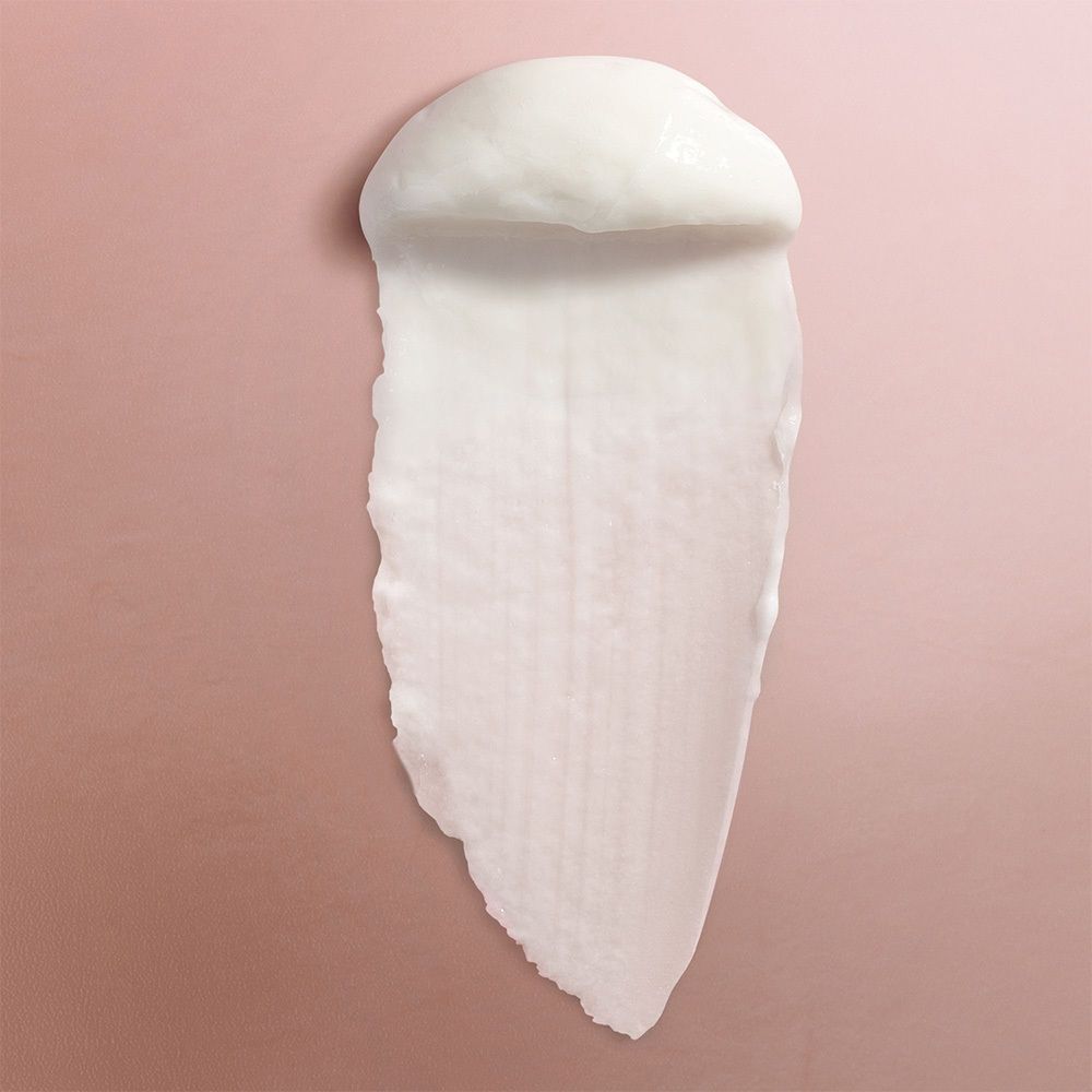 Texture crème blanche sur fond rose. Trace allongée.