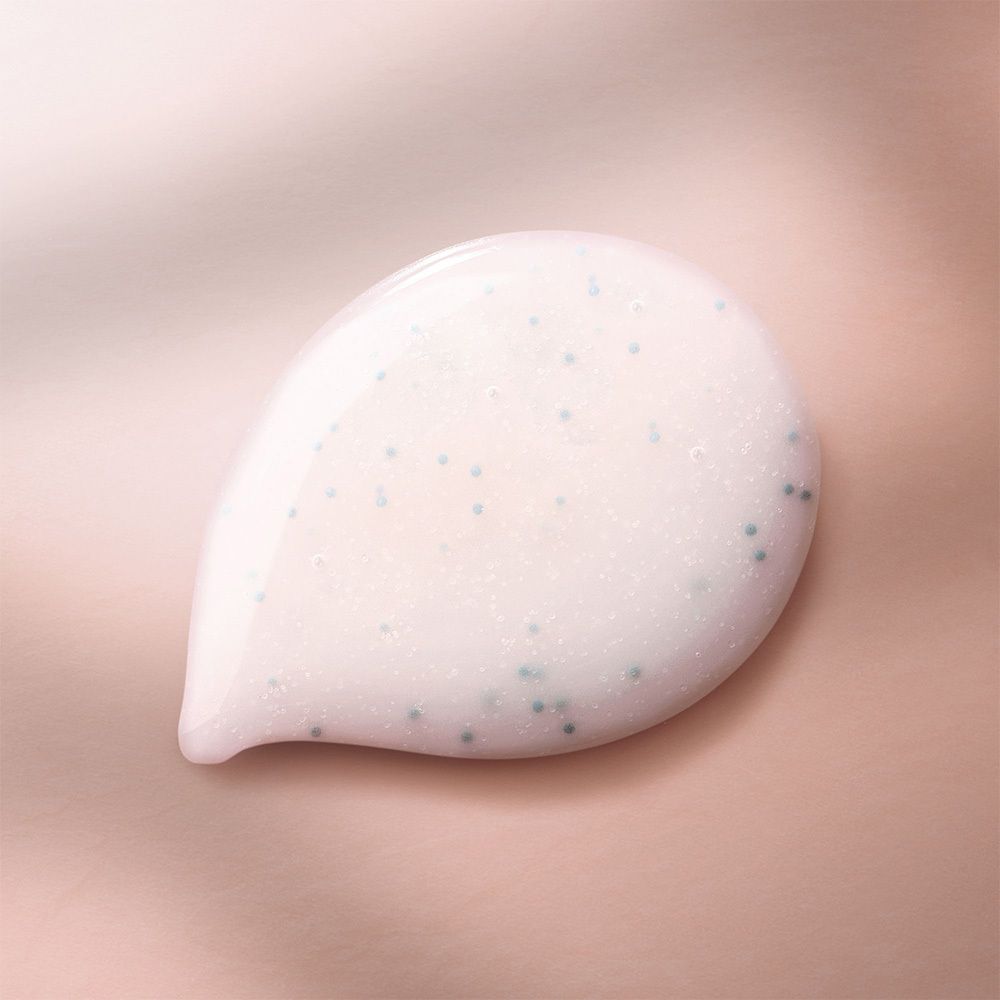 Gros plan d'un gel blanc avec de petites particules bleues sur fond rose. En forme de goutte.