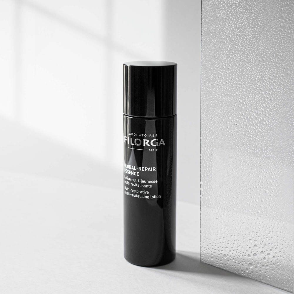 FILORGA Global-Repair Essence. Flacon noir devant miroir. Nom et informations du produit.