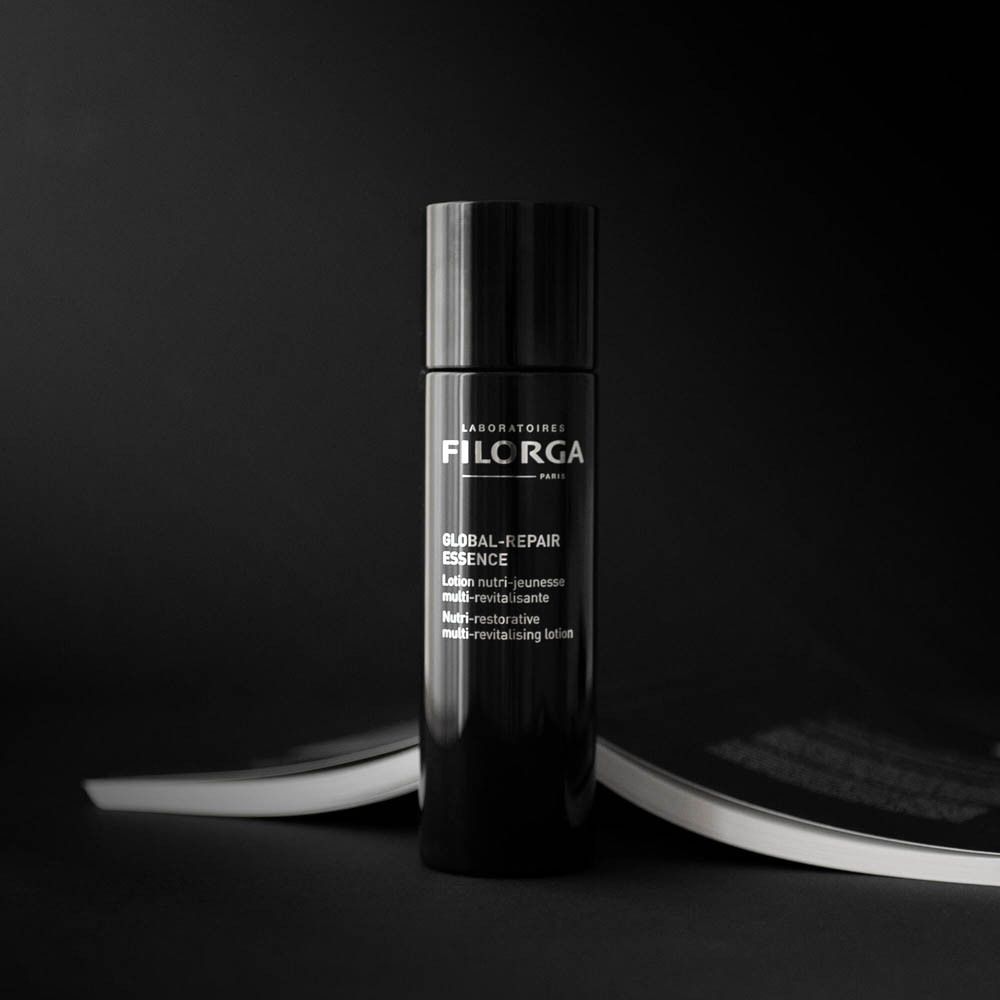 FILORGA Global-Repair Essence. Flacon noir sur fond sombre. Nom et informations du produit.