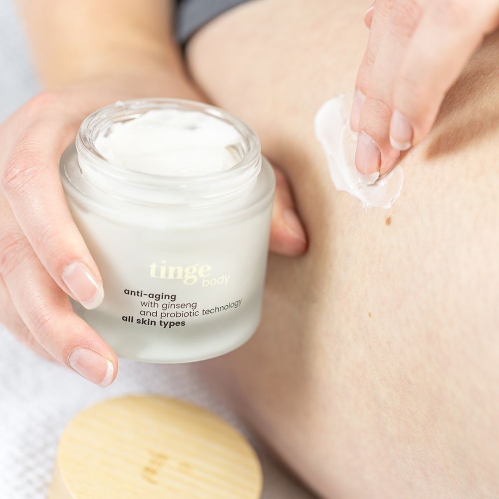 Une main applique la Tinge Bodylotion Anti-Aging sur la peau.