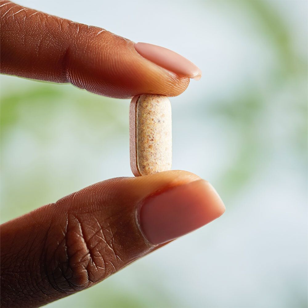 Main tenant un comprimé oblong entre les doigts.