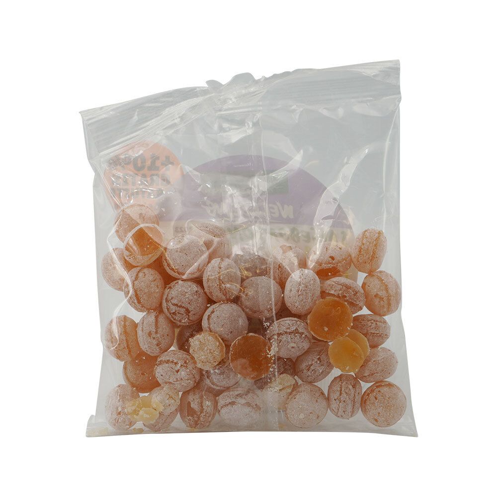 Sachet plastique transparent rempli de bonbons orangés. Bonbons ronds et légèrement translucides.