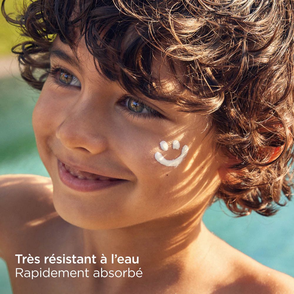 Garçon avec un smiley de crème solaire sur le visage. Texte: Très résistant à l'eau, Rapidement absorbé.