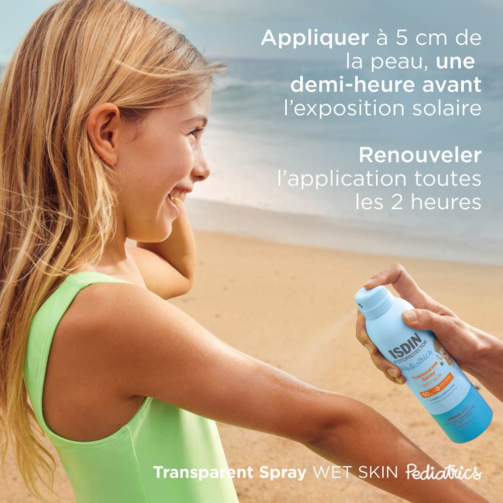 Enfant vaporisant ISDIN Fotoprotector Pädiatrie Transparent Spray Wet Skin SPF50+ sur le bras. Plage.