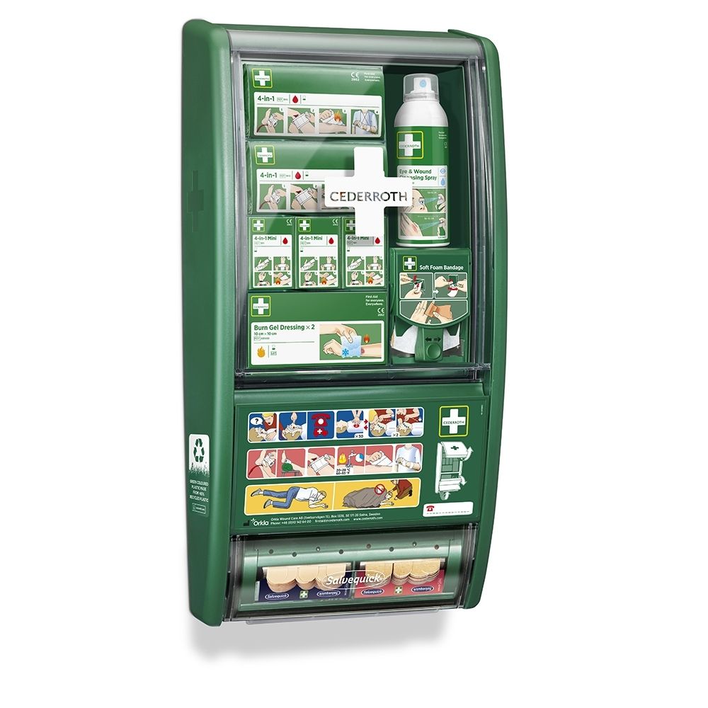 Station de premiers secours verte avec couvercle transparent, remplie de matériel de premiers secours et d'instructions.
