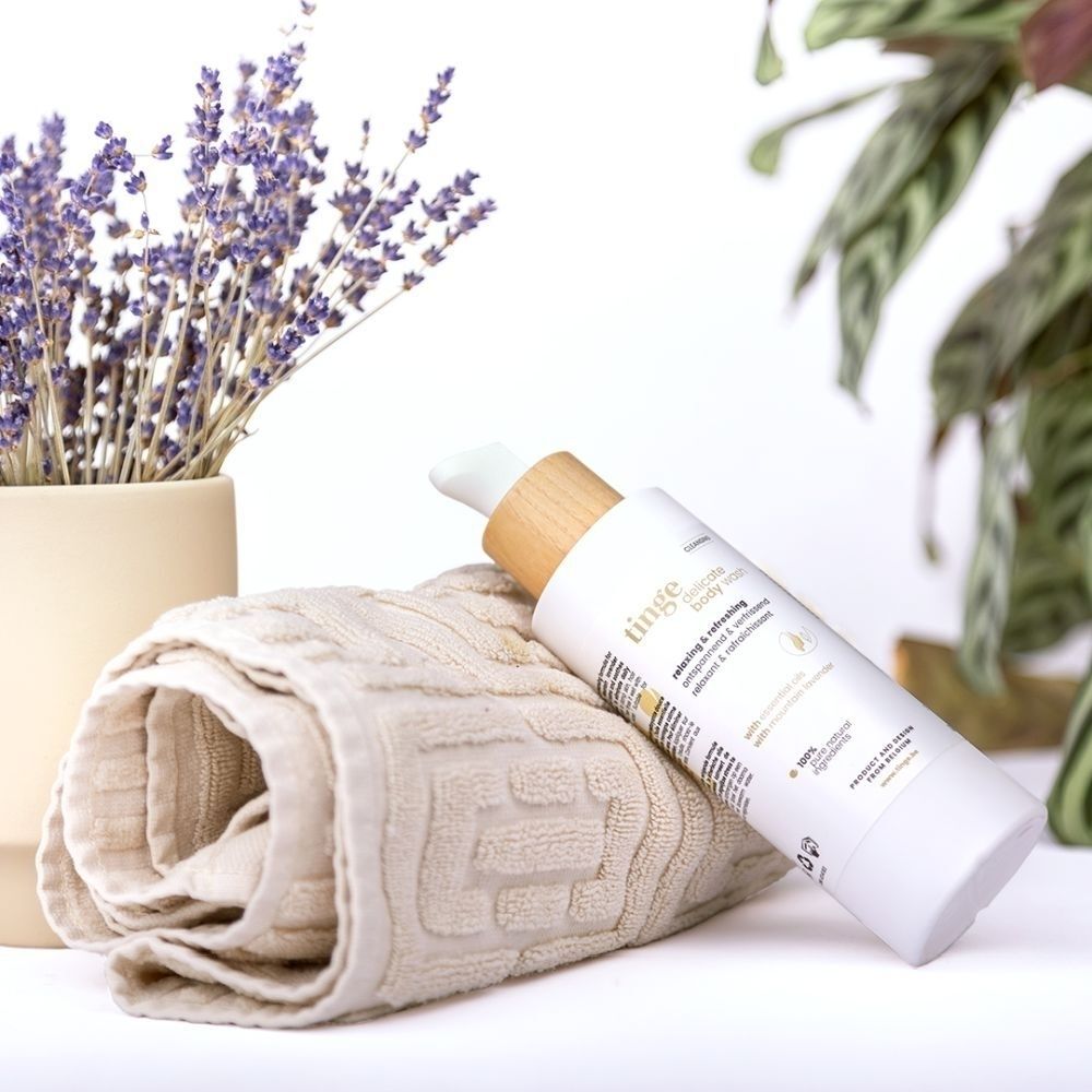 Tinge Delicate Body Wash à côté d'une serviette et de lavande.