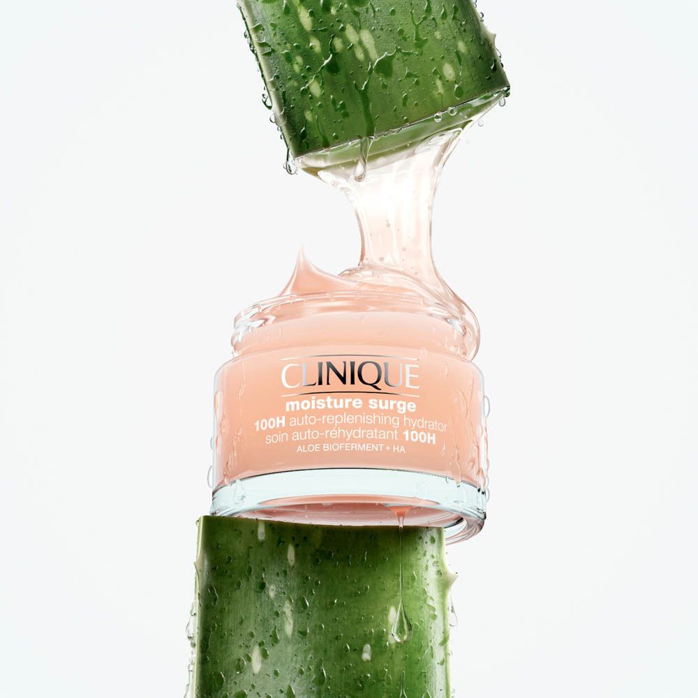 Un pot de CLINIQUE Moisture Surge 100H Auto-Replenishing Hydrator entre des morceaux d'aloe vera.