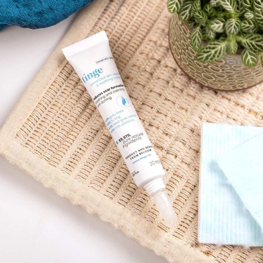Tube Tinge Advanced Skin Repair & Soothing Cream sur texture. Texte français.