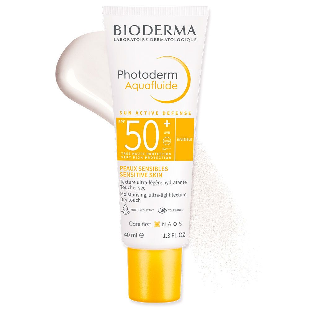 Tube blanc Bioderma Photoderm Aquafluide SPF50+. Bouchon jaune. Crème blanche à côté. Texte: Peaux Sensibles.